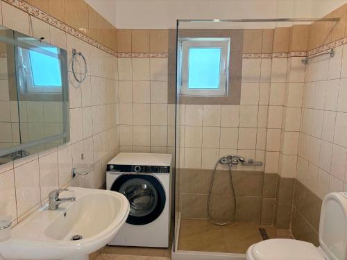 a bathroom with a washing machine and a sink at Dimitris House in Pllakë