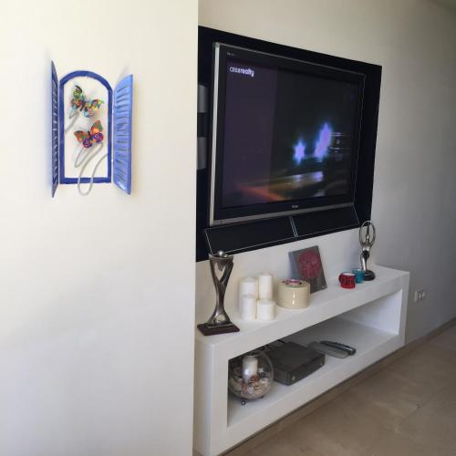 a flat screen tv sitting on top of a white shelf at Raphael Apartments in Herzelia 