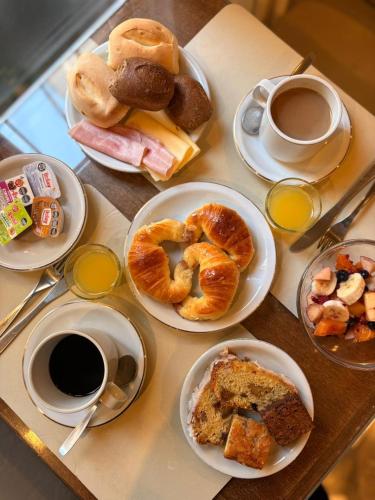 a table topped with plates of pastries and cups of coffee at Hotel Selent in Mar del Plata