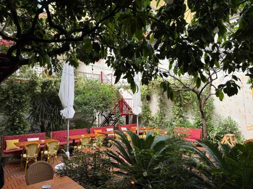 a patio with tables and chairs and white umbrellas at SMALL Boutique & Garden in Tirana