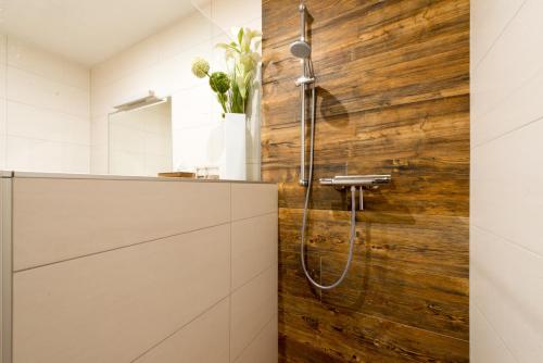 La salle de bains est pourvue d'une douche et d'un mur en bois. dans l'établissement Appartement Kufsteinblick, à Haus im Ennstal
