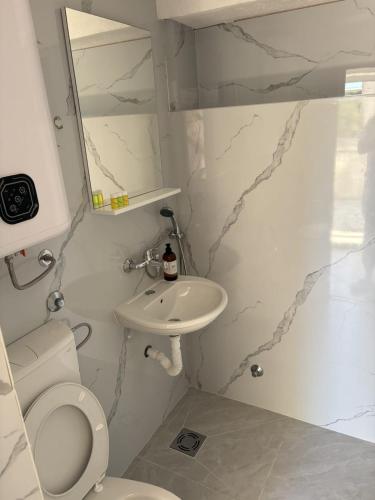 a white bathroom with a toilet and a sink at Apartments Sole1 in Sutomore