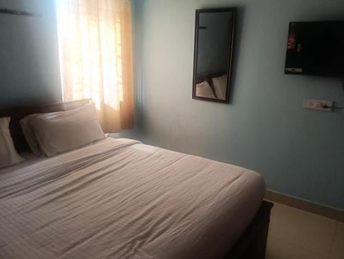 a bedroom with a white bed with a television on the wall at coastal charm in Chennai