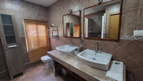 a bathroom with two sinks and a toilet and mirrors at Villa Alfaguara-Holiday Home Granada & Sierra Nevada in Granada