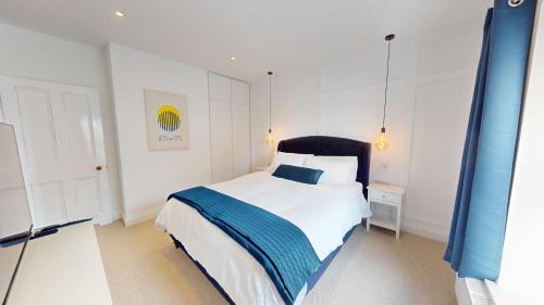 a bedroom with a white bed with a blue blanket at Sheringham Luxury, Cinema, Hot Tub & Beach in Sheringham