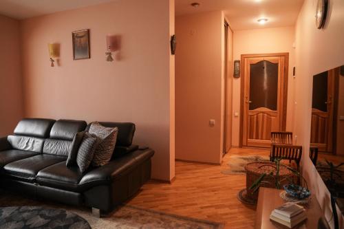 a living room with a black leather couch and a door at Nida Center Studio Apartment in Neringa