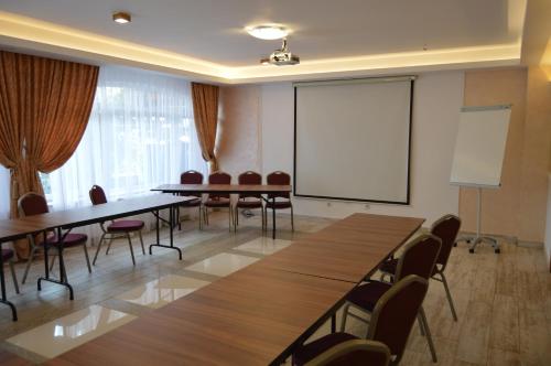 a conference room with tables and chairs and a projection screen at Hotel Bulevard Prestige in Slatina