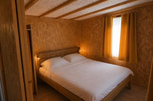 a bedroom with a white bed with a window at Tiny House nearby Spa Francorchamps in Amblève