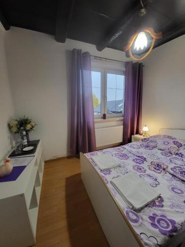 a bedroom with a bed and a window with purple curtains at Villa Patria Wadowice in Wadowice
