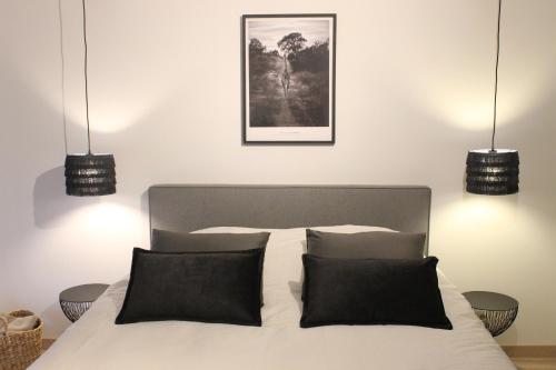 a bedroom with a bed with black pillows and two lights at Les Clefs de Godefroy in Bouillon