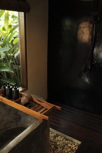 a bathroom with a bath tub with a window at YŪN Uluwatu in Uluwatu