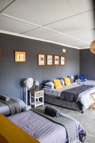 a bedroom with two beds and a wall with pictures at Kwelanga River Lodge in Vioolsdrif