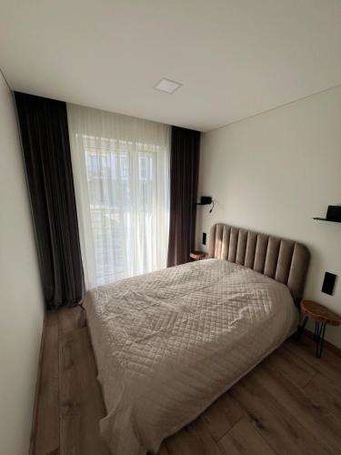 a bedroom with a large bed and a window at Cozy Home Oasis in Palanga
