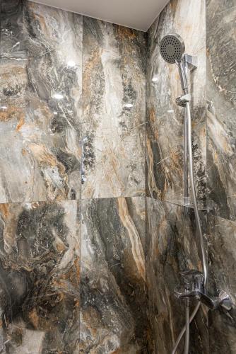 a shower in a bathroom with a stone wall at Vila Uosis in Palanga