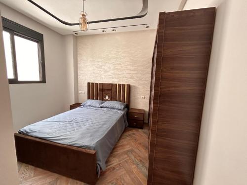 a bedroom with a bed and a large wooden closet at Jaouhar immo in Martil