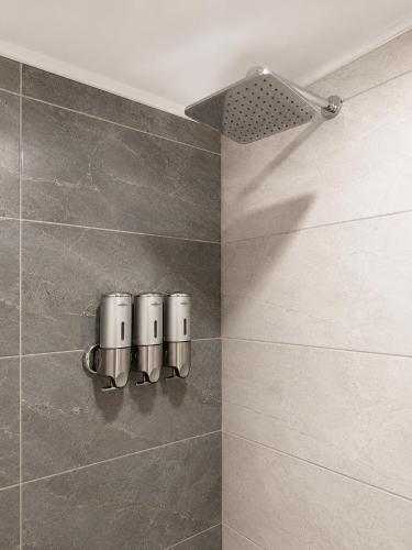 a bathroom with a shower with three cups on the wall at Ber Mai İnci Hotel Antalya in Antalya