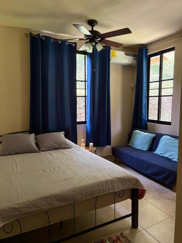 a bedroom with blue curtains and a bed and a fan at Casa Flussy in Sorá
