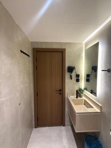 a bathroom with a sink and a wooden door at سويت إبرام- بتصميم فاخر بدخول ذاتي in Dammam