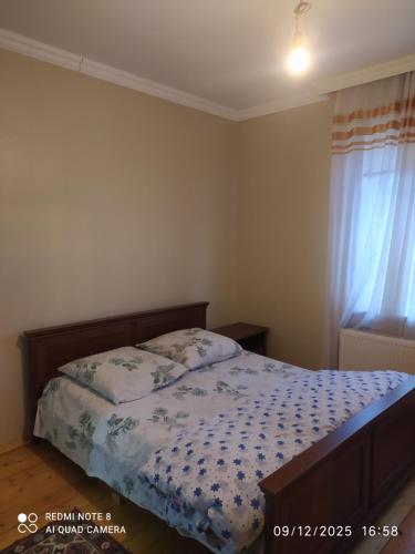 a bedroom with a bed with a blue and white comforter at Gabala,yard, house in Gabala