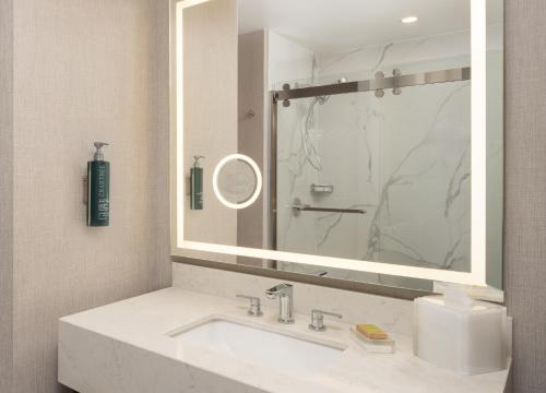 a bathroom with a sink and a large mirror at Hilton Houston North in Houston