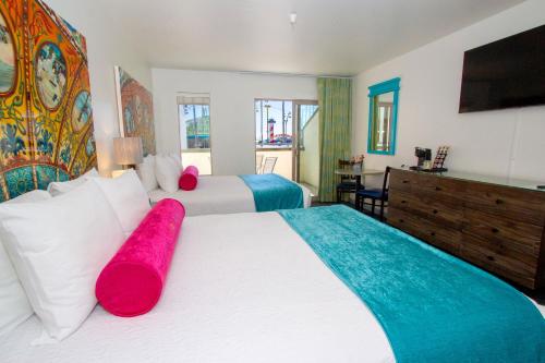 a bedroom with two beds and a flat screen tv at Carousel Beach Inn in Santa Cruz