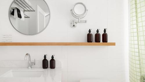 a bathroom with a mirror and black bottles on a shelf at The Penny Lane in Hampton Bays