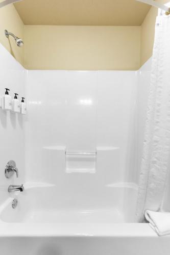 a white bathroom with a tub and a sink at Cobblestone Inn & Suites - Bloomfield in Bloomfield