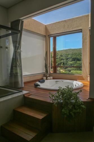 a large bathroom with a tub and a large window at Chalé Jenipapo in Serra do Cipo