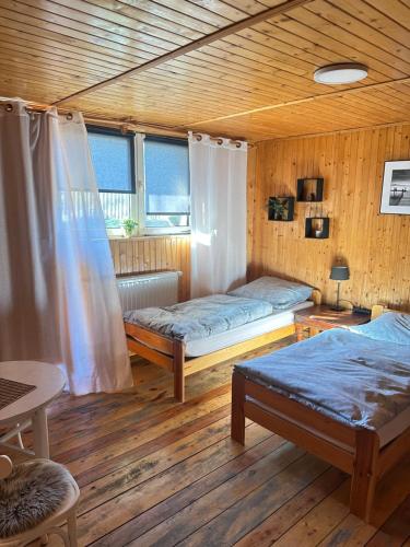 two beds in a room with wooden walls and wood floors at Dom Pod Lasem in Korbielów