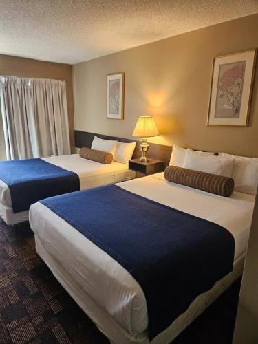 a hotel room with two beds with blue sheets at Alaskan Motel in Fox Creek