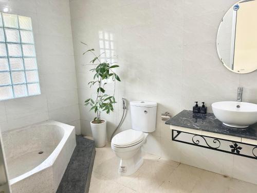 a white bathroom with a toilet and a sink at Villa Rosa HueS in Thôn An Hòa