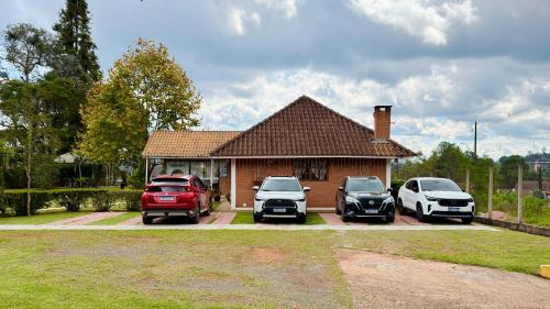 a house with three cars parked in front of it at Pousada Villa do Luar by Concavus in Monte Verde