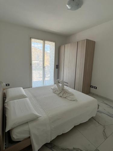 a bedroom with a large white bed with a large window at Appartamenti Gemma in Calmasino