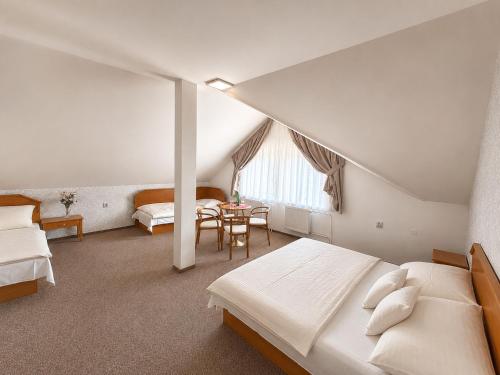 a attic bedroom with two beds and a table at Hotel Casanova in Duchcov