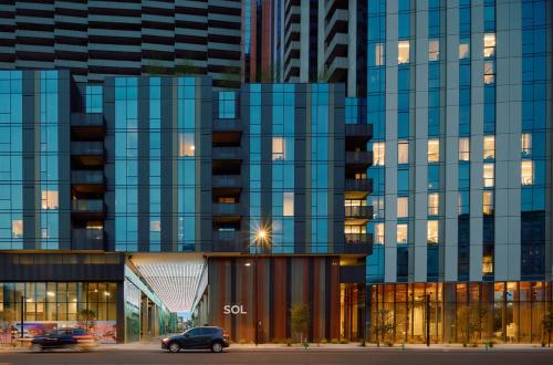 a large glass building with cars parked in front of it at Sentral Sol Modern in Phoenix