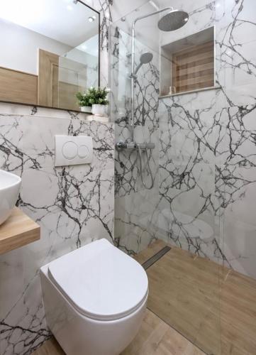 a bathroom with a white toilet and a shower at Apartments & Rooms Iva in Vrbnik
