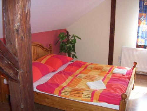1 dormitorio con cama de madera y edredón colorido en Penzion U červených vrat, en Chudolazy