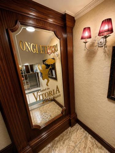 a mirror on a wall with a picture in a room at Hotel Ciudad de Vitoria in Santiago