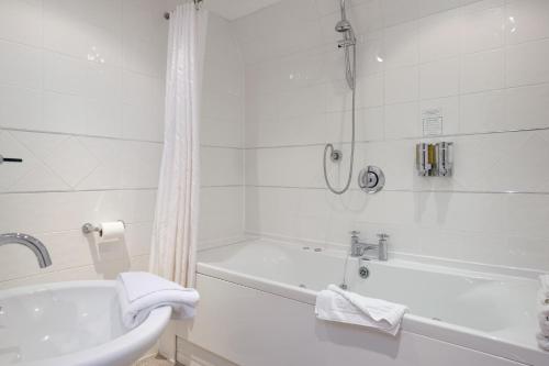 a white bathroom with a tub and a sink at The Cathedral Hotel in Lichfield