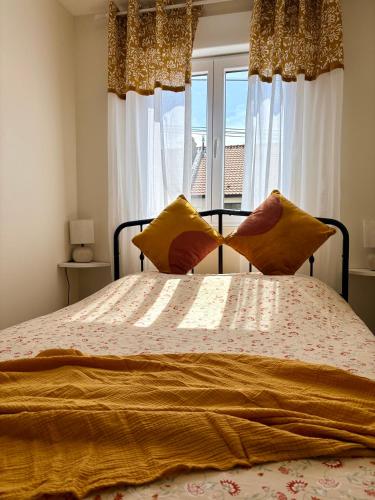 a bedroom with a bed with yellow pillows and a window at L'Échappée iodée à "La Cahute" - Rénovée, Calme & Proche Mer in Ambleteuse
