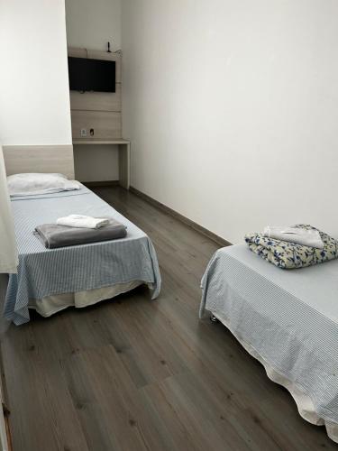 a room with two beds and a tv on a wall at HL Hotel in Pelotas