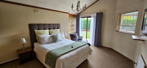 a bedroom with a bed and a chair and a window at Applegate lodge in Clarens