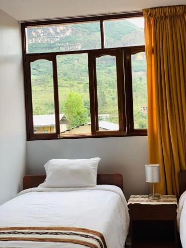 a bedroom with two beds and a large window at Hostal Gocta in Cocachimba