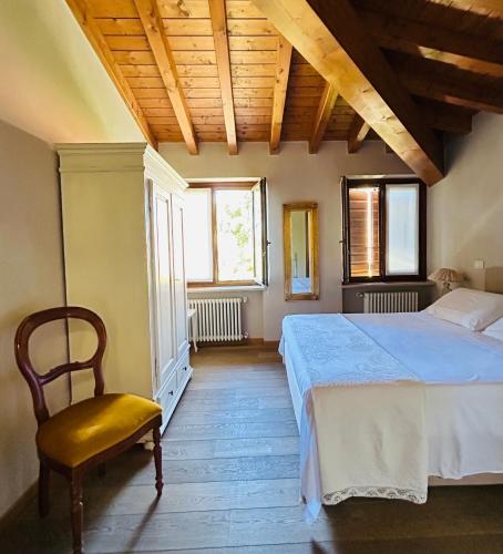 a bedroom with a bed and a chair and windows at Ca Malfer in Costermano sul garda