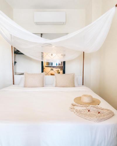a hat on a bed with white curtains at Beachfront - Private Floor, 4 Rooms - Casa 3 Lunas in Playa Agua Blanca