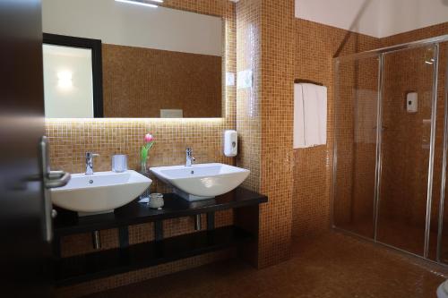a bathroom with two sinks and a shower and a mirror at Hotel Admeto in Marinella di Selinunte