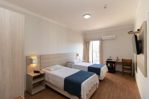a hotel room with two beds and a desk at Bristol Zaniboni Mogi Mirim in Mogi Mirim