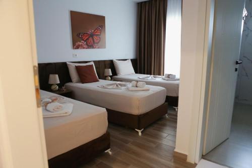 two beds in a hotel room with a butterfly painting on the wall at Bebis Rooms in Orikum
