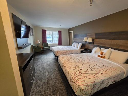 a hotel room with two beds and a flat screen tv at Roosevelt Inn Mount Rushmore in Keystone