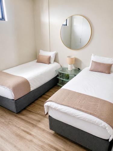 two beds in a room with a mirror at Movic's Modern Airbnb in Windhoek